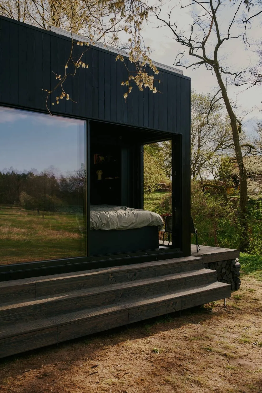 StayRaus-Kabine mit Glasfront und Holzstufen am Waldrand